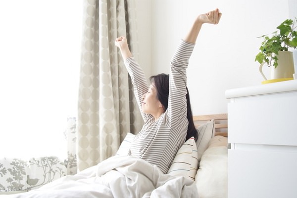 ベッドで伸びをする女性