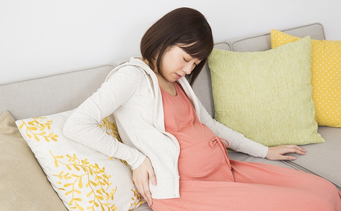 腰を手で押さえる妊婦